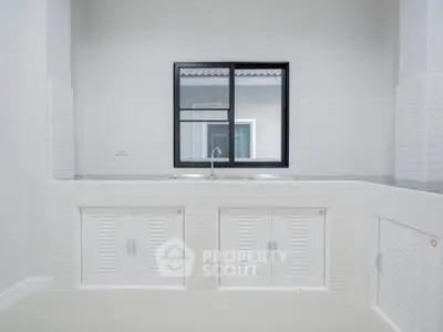 Modern minimalist kitchen with sleek white cabinetry and large window