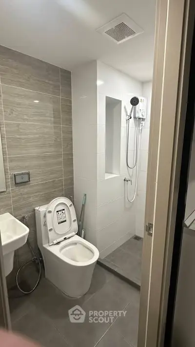Modern bathroom with sleek design featuring a toilet, sink, and shower area with contemporary fixtures.