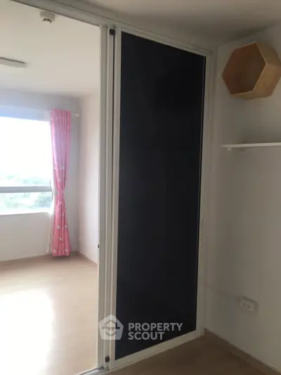 Bright room with large window and pink curtains, featuring a modern sliding door and wooden flooring.