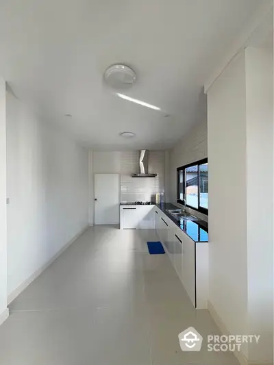 Modern minimalist kitchen with sleek white cabinetry and large window view