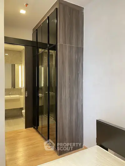 Modern bedroom with sleek wardrobe and ensuite bathroom in stylish apartment.