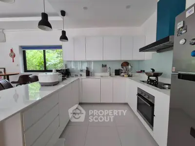 Modern kitchen with sleek white cabinets and appliances, featuring an open layout and natural light.