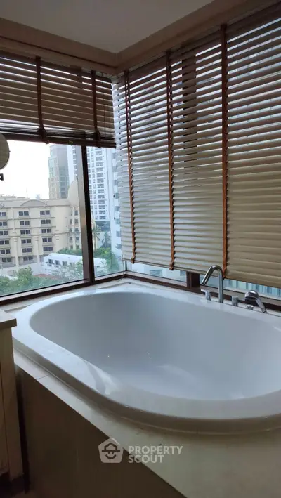 Luxurious bathroom with a large bathtub and city view, perfect for relaxation.