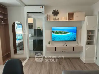 Modern living room with sleek TV setup and stylish decor, featuring a glimpse into a cozy bedroom.