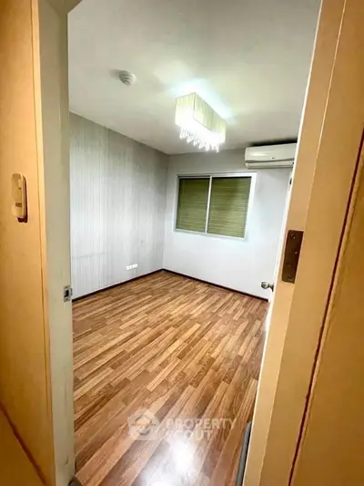 Spacious empty room with wooden flooring and modern lighting, perfect for customization.