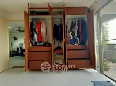 Spacious bedroom with open wardrobe and sliding glass doors to balcony.