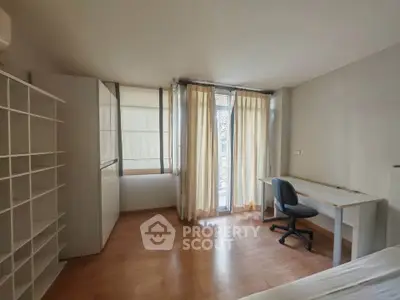 Spacious bedroom with natural light, wooden flooring, and study desk near window.
