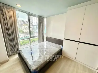 Modern bedroom with large window and city view, featuring a comfortable bed and sleek wardrobe.