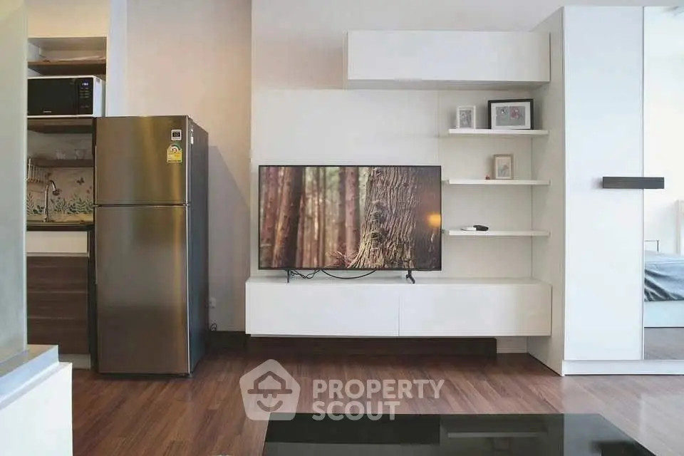 Modern living room with sleek TV setup and stainless steel fridge