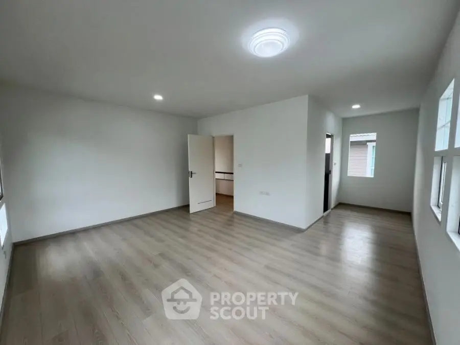 Spacious empty room with wooden flooring and modern lighting, ideal for customization.