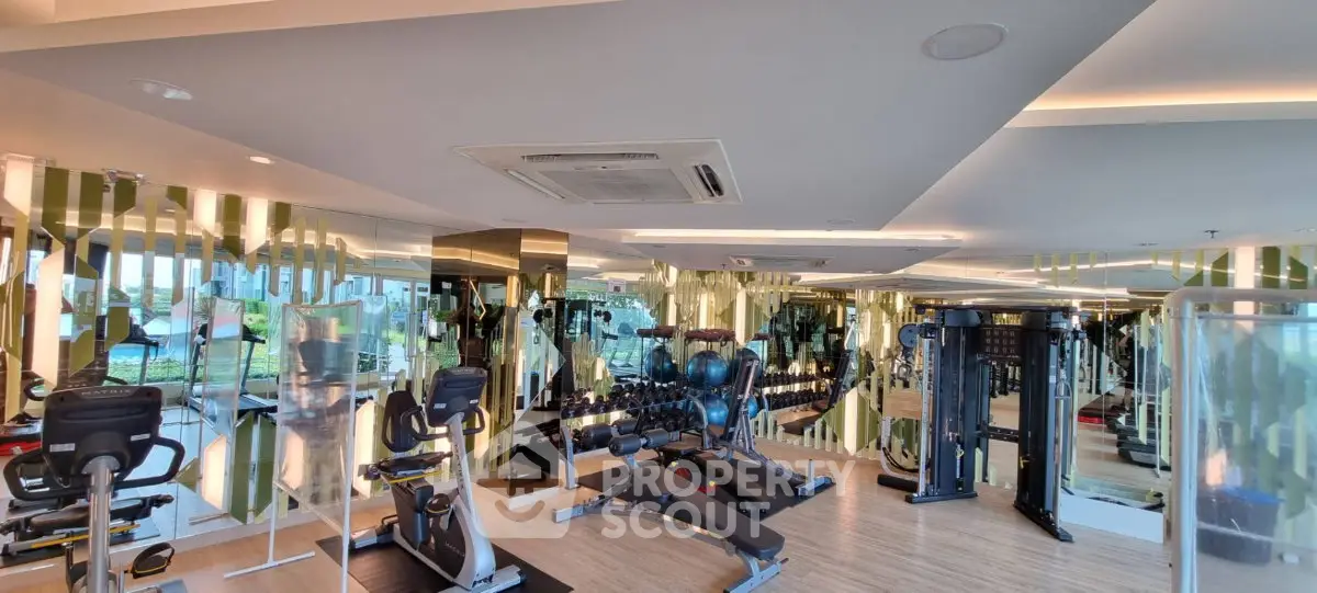Luxurious gym with modern equipment and mirrored walls in upscale residential building.