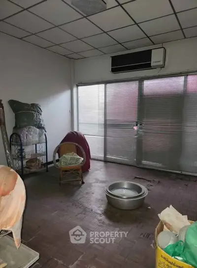 Spacious room with air conditioning and large windows, ideal for storage or creative use.