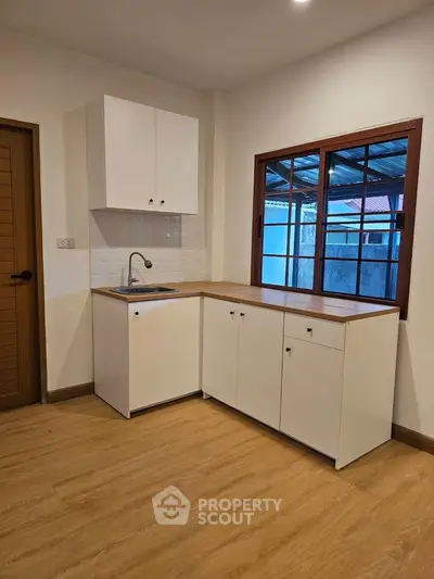 Modern kitchen with wooden flooring and minimalist white cabinets