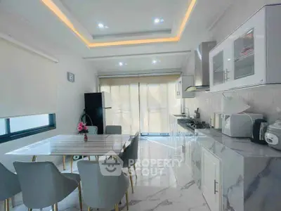 Modern kitchen with sleek design, marble countertops, and dining area in bright open space.