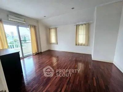 Spacious room with wooden flooring and balcony access in modern apartment