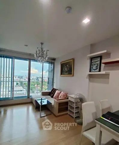 Modern living room with chandelier and city view, featuring stylish decor and ample natural light.