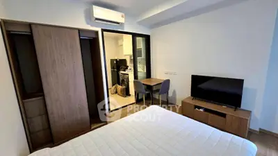 Modern bedroom with sleek furniture and open view into kitchen area, perfect for urban living.