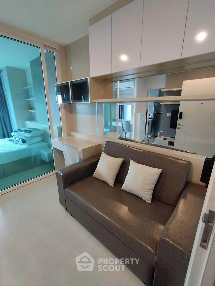 Modern living room with sleek sofa and stylish shelving in a compact apartment setting.