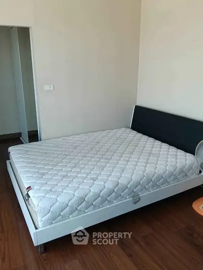 Spacious bedroom with modern bed and wooden flooring, perfect for a cozy retreat.