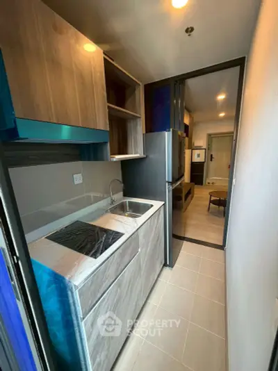 Modern compact kitchen with sleek cabinetry and integrated appliances in a stylish apartment.