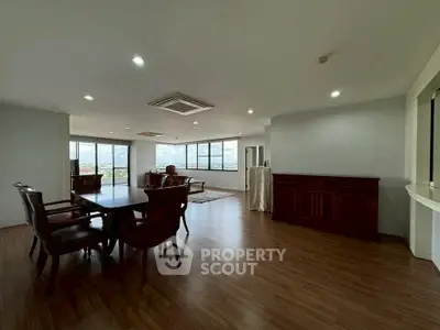 Spacious open-plan living room with wooden flooring and panoramic city views.