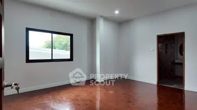 Spacious empty room with wooden flooring and large window