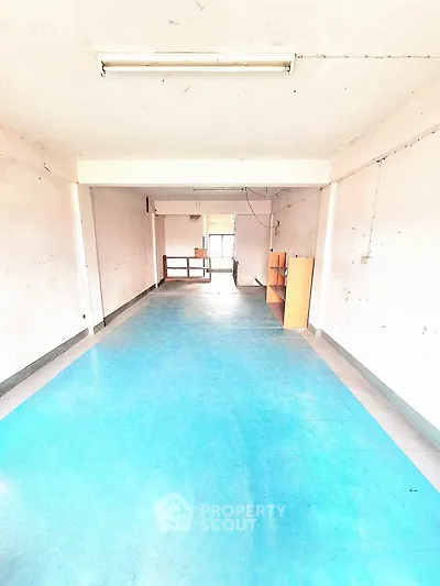 Spacious interior with bright blue flooring and ample natural light, ideal for versatile use.