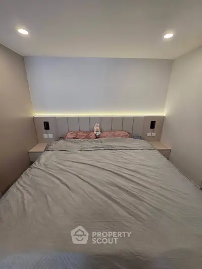 Cozy bedroom with modern lighting and plush bedding, perfect for relaxation.