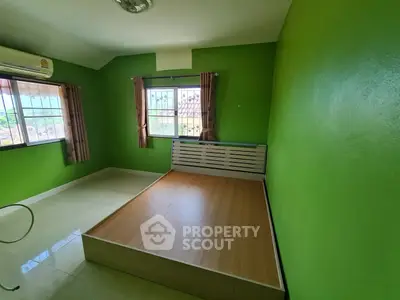 Vibrant green-walled bedroom with ample natural light, featuring a large bed frame and charming curtains, perfect for personalizing your restful retreat.