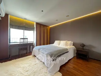 Spacious bedroom with cozy decor and large window for natural light