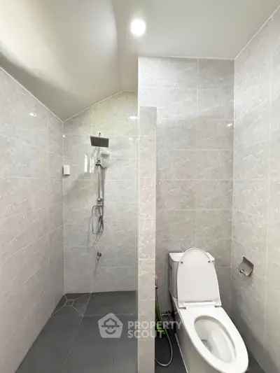 Modern bathroom with sleek gray tiles and a spacious shower area.