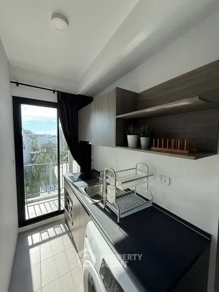 Modern kitchen with sleek design and balcony view, featuring washer and ample storage space.
