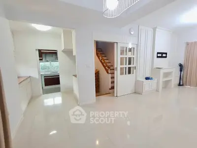 Spacious open-plan living area with modern kitchen and staircase, perfect for family living.