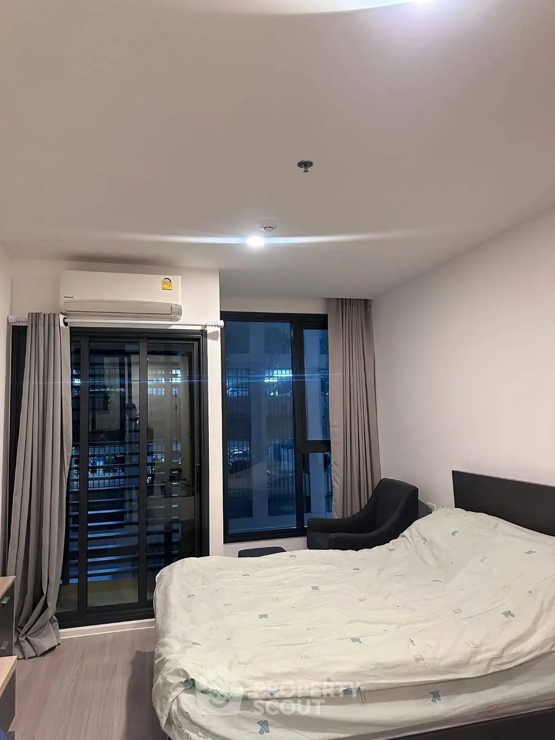 Modern bedroom with large windows and air conditioning in a stylish apartment.