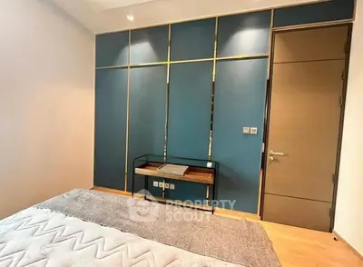 Modern bedroom with stylish blue accent wall and sleek furniture.