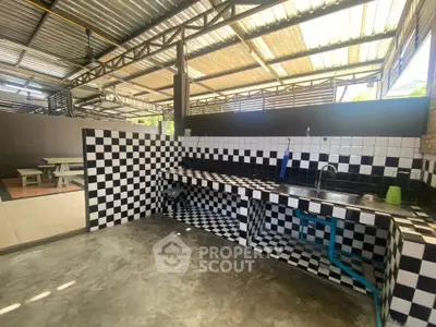 Spacious industrial-style kitchen with checkered tiles and open layout, perfect for culinary creativity.