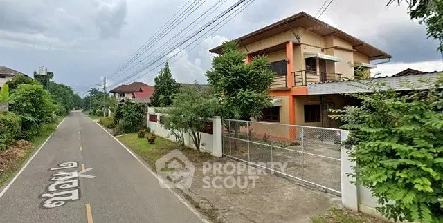 Charming two-story house with gated driveway and lush greenery on a quiet street.