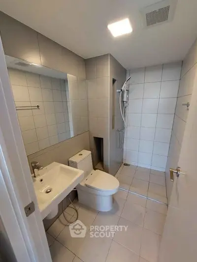 Modern bathroom with sleek fixtures and spacious shower area in a contemporary apartment.