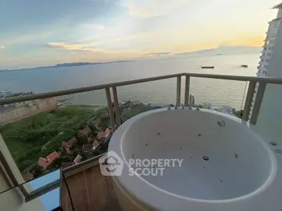 Luxurious balcony with jacuzzi offering stunning ocean views at sunset.
