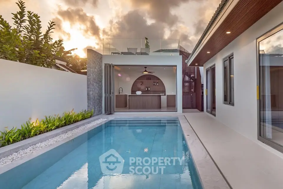 Luxurious modern villa with private pool and stylish outdoor kitchen at sunset.