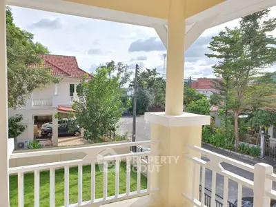 Charming balcony view of suburban neighborhood with lush greenery and elegant houses.