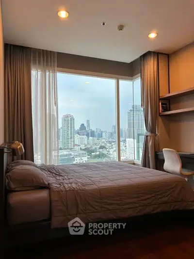 Modern bedroom with stunning city view and cozy decor in high-rise apartment.