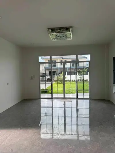 Spacious interior with large windows offering a view of the garden and neighboring house.