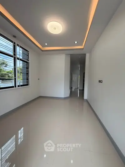 Spacious modern room with sleek lighting and large window, perfect for versatile living space.
