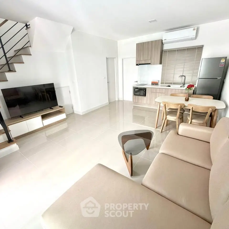 Modern open-plan living room with sleek kitchen and stylish furniture in a bright, airy space.