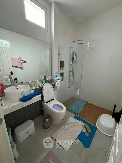 Modern bathroom with glass shower, stylish sink, and bright natural light.