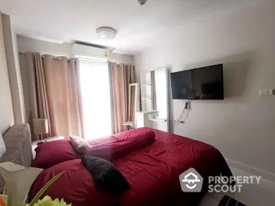 Modern bedroom with red bedding, wall-mounted TV, and natural light from large window.