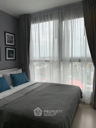 Modern bedroom with large windows offering stunning city views and elegant decor.