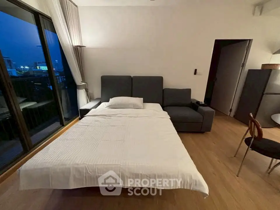 Modern bedroom with sofa bed and balcony view in urban apartment