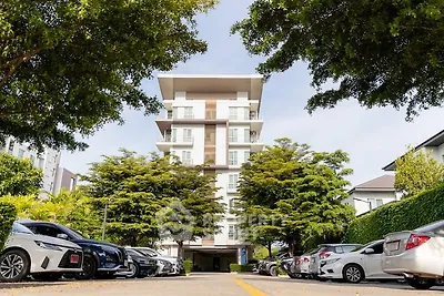 Modern apartment building with lush greenery and ample parking space